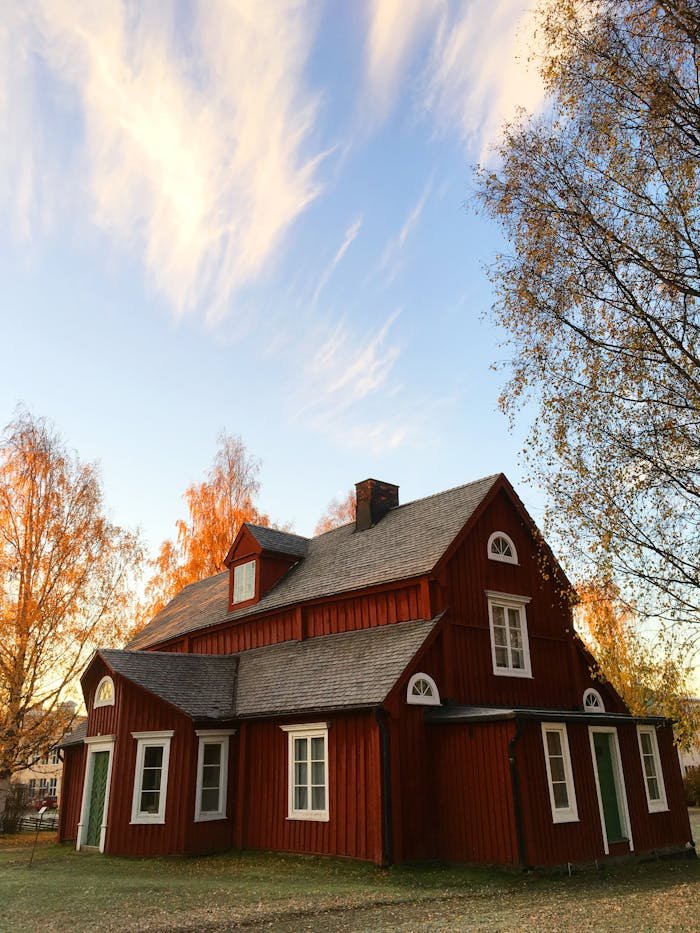 Services-01 Picturesque red wooden house in autumn. Traditional Swedish architecture amidst colorful foliage.